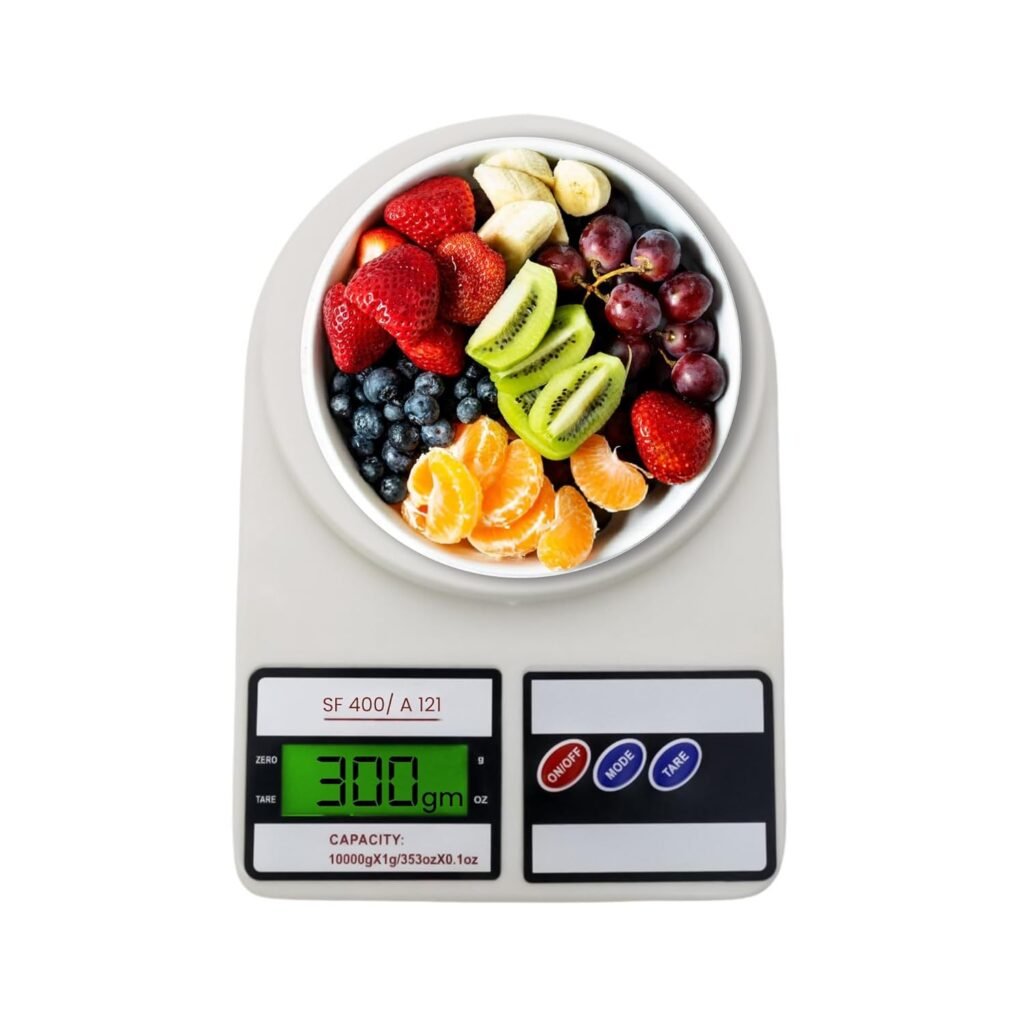 Digital kitchen weighing scale with LCD display measuring a bowl of mixed fruits including strawberries, kiwi, grapes, blueberries, bananas, and oranges.