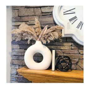 White ceramic decorative vase with dried pampas grass on a wooden shelf